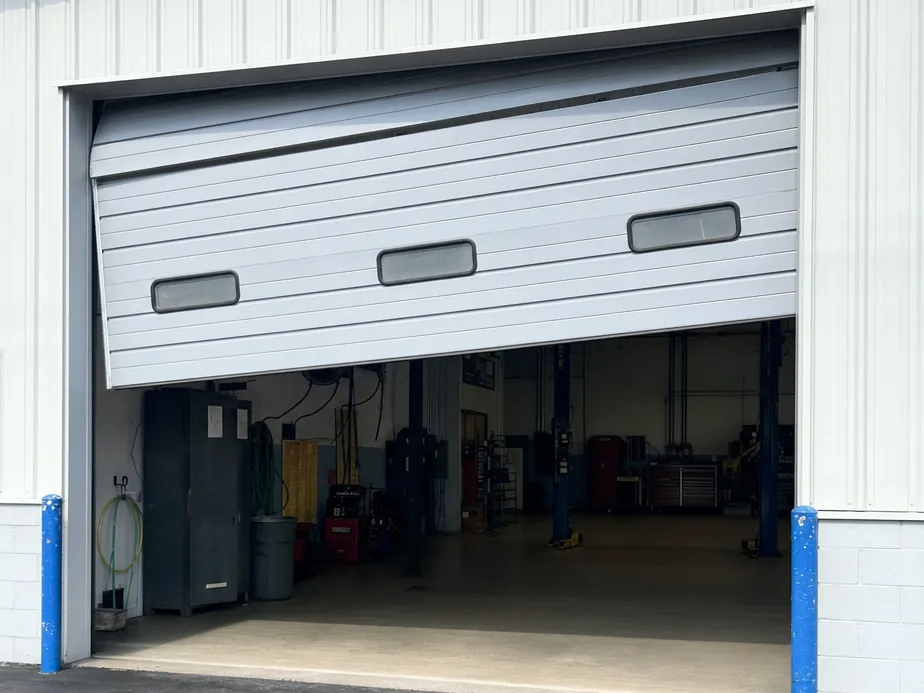 Commercial sectional garage door hanging crooked in a repair bay opening